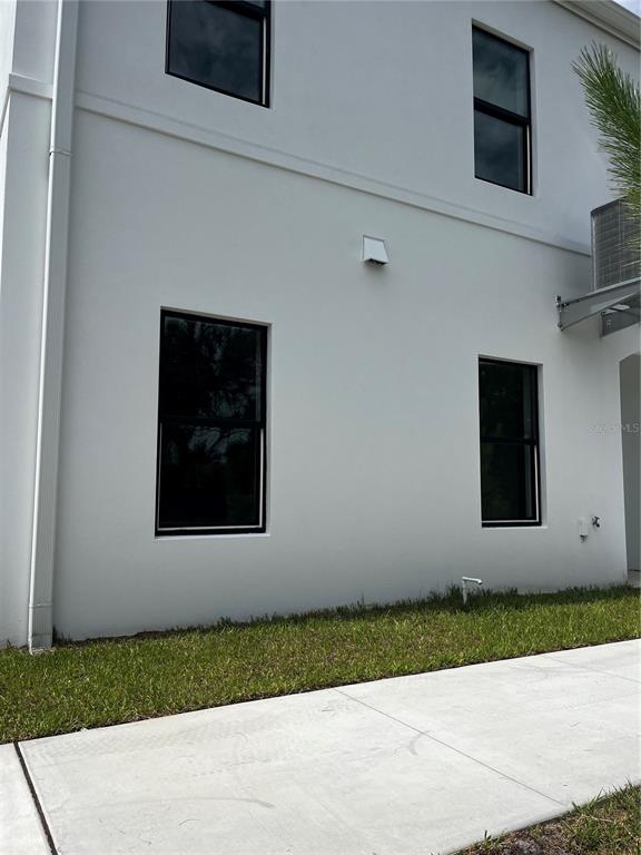 The exterior of a white two-story building features black-framed windows and a concrete walkway — 4363 CAMBIO GARDENS COURT, TAMPA, FL