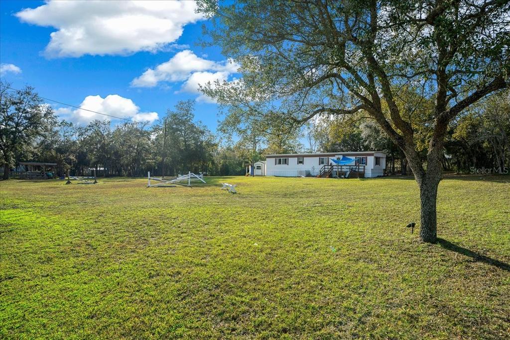 A mobile home sits on a large, grassy lot with several trees and white fencing — 6250 SE 150TH AVENUE, MORRISTON, FL