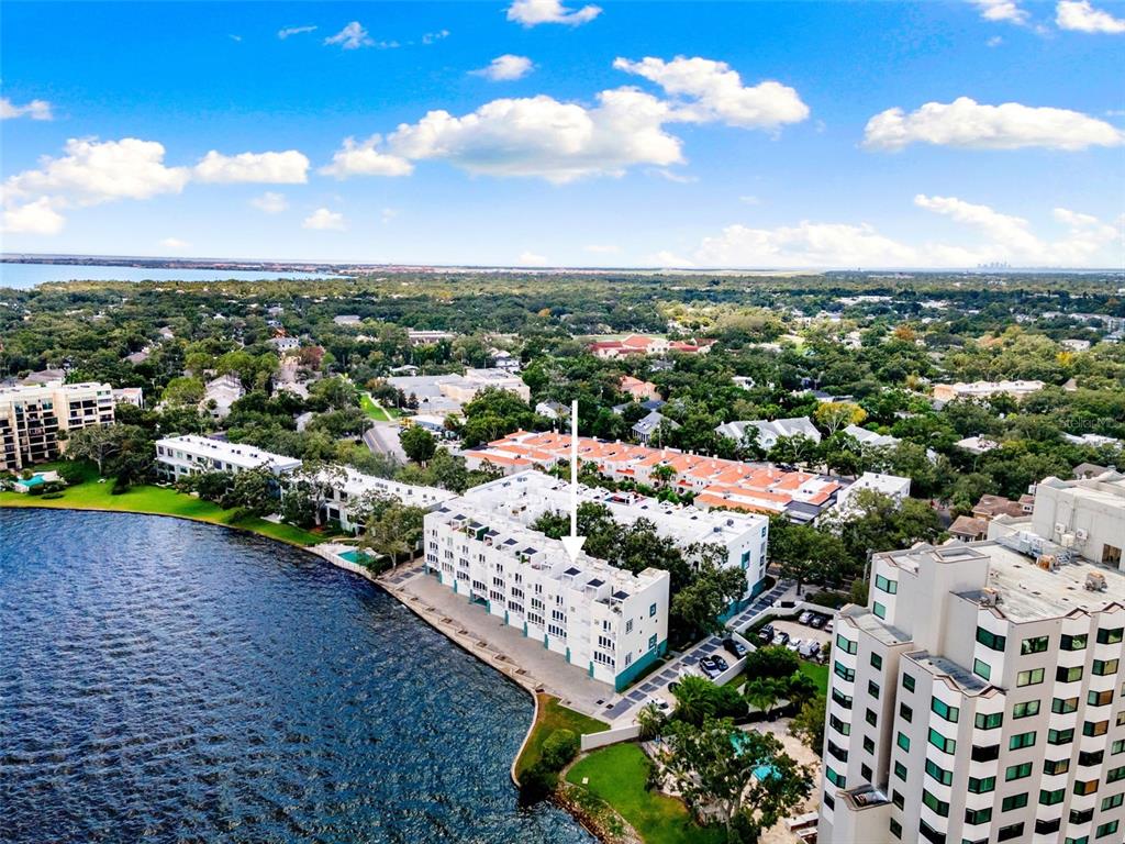An aerial view shows a multi-story waterfront apartment building with a white arrow pointing down — 4950 BAYSHORE BOULEVARD UNIT 23, TAMPA, FL