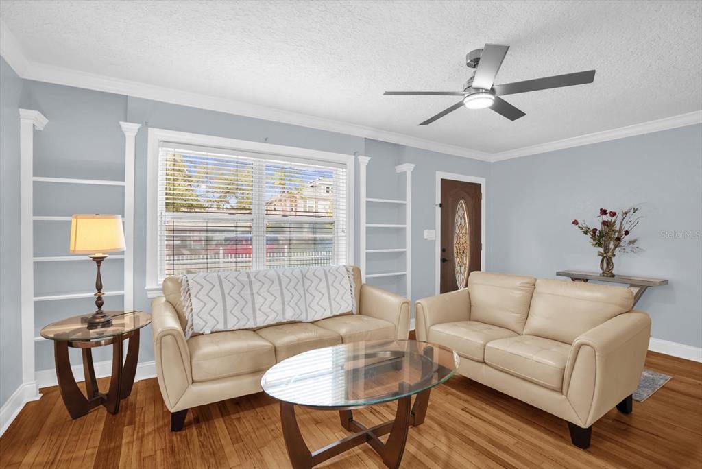 A living room features light blue walls, two beige sofas, a glass coffee table, and shelving — 918 W SMITH STREET, ORLANDO, FL