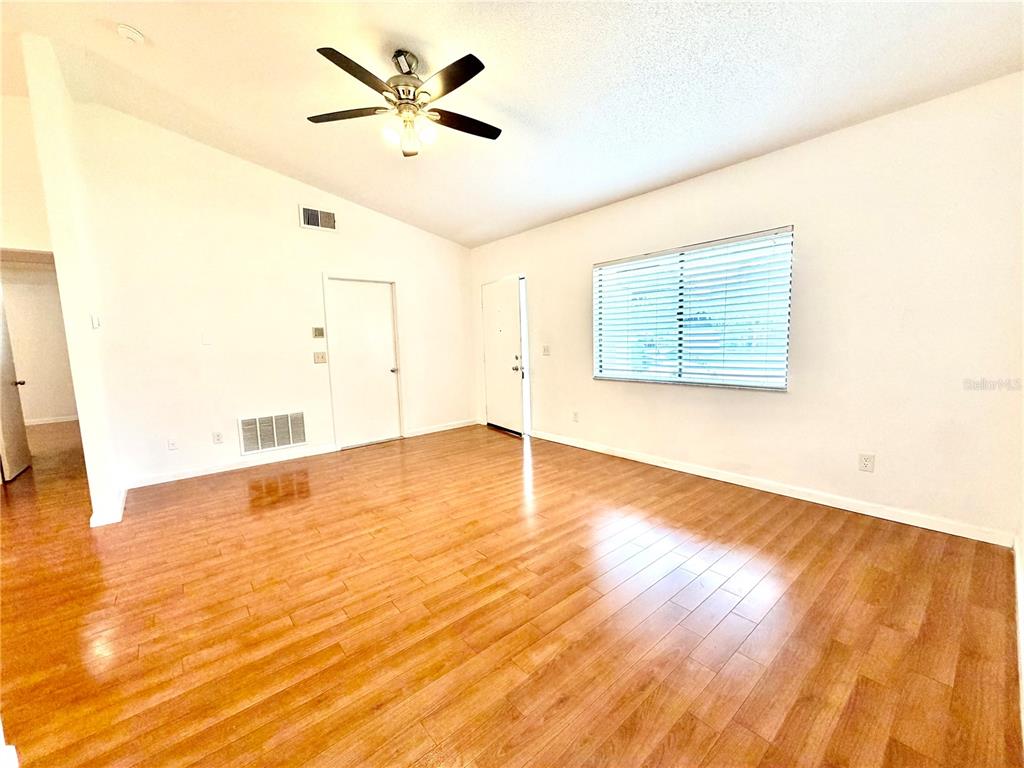 An empty room features light wood-look flooring, white walls, a ceiling fan, and a window — 3349 SASSAFRAS COURT, ORLANDO, FL