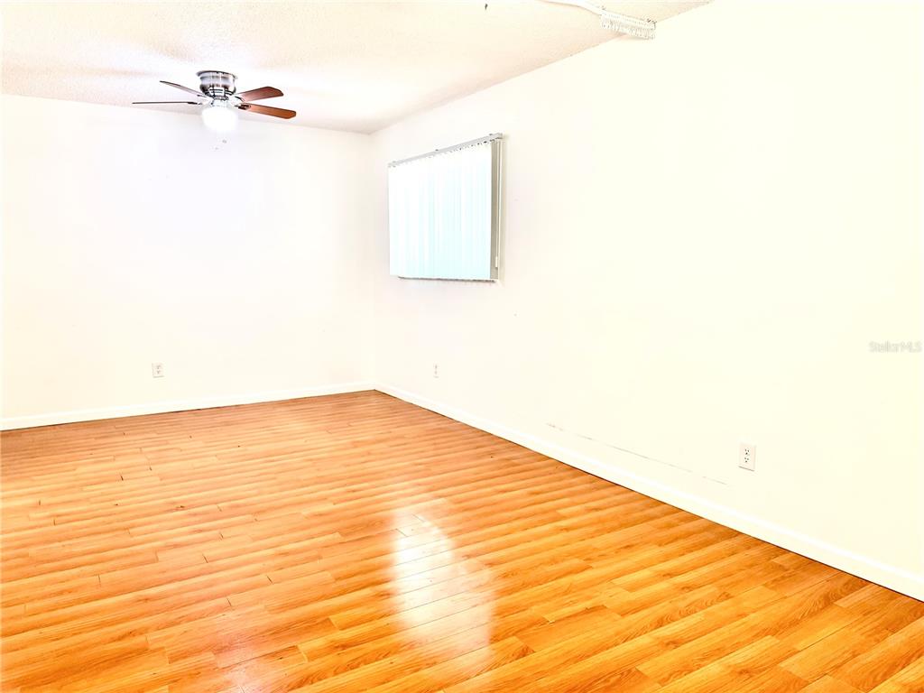 An empty room features light wood-look flooring, white walls, a ceiling fan, and vertical blinds — 3349 SASSAFRAS COURT, ORLANDO, FL