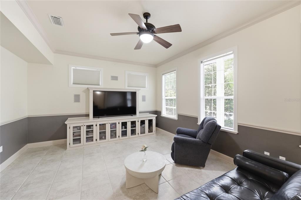 A living room features a large television, built-in white cabinetry, tile flooring, and a ceiling fan — 9255 SW 29 AVENUE, GAINESVILLE, FL