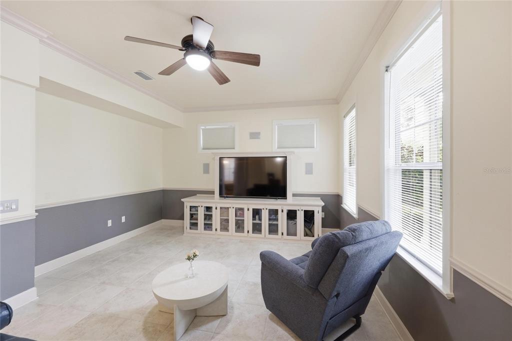 A living room features a ceiling fan, a television console, and gray wainscoting — 9255 SW 29 AVENUE, GAINESVILLE, FL