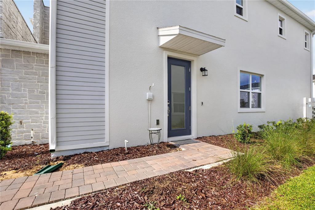 A paved walkway leads to a blue front door on the side of a house — 198 NINE IRON DRIVE, CHAMPIONS GATE, FL