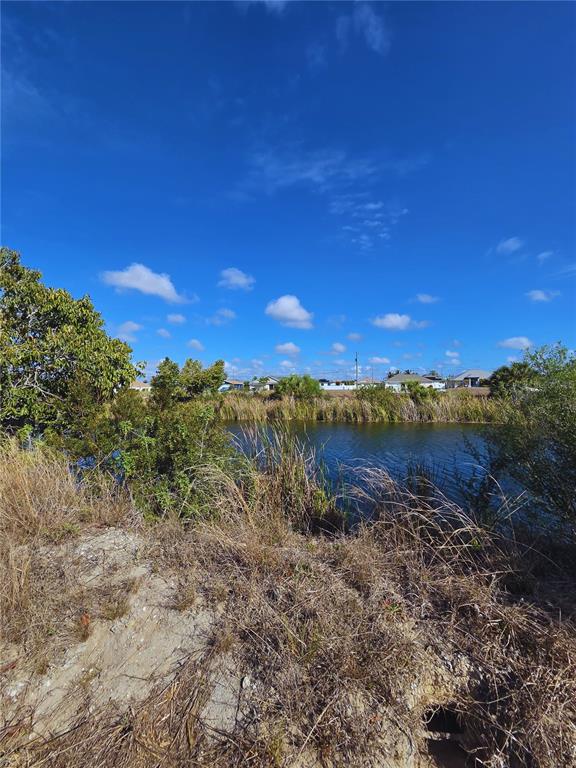 A view of a grassy bank overlooking a canal with houses in the distance — 1029 NW 18TH STREET, CAPE CORAL, FL
