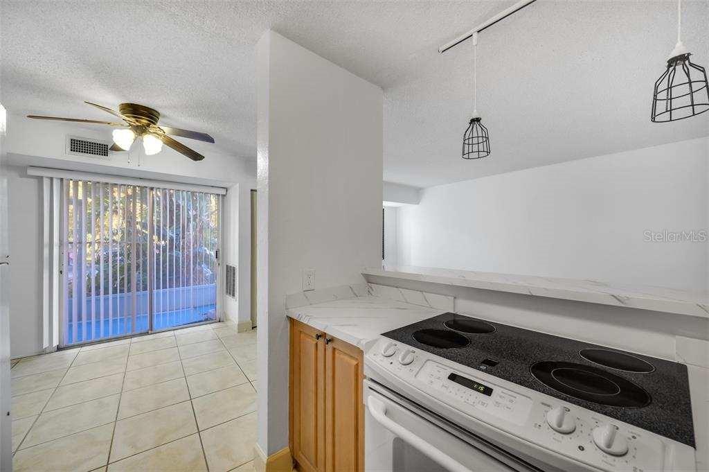 A kitchen with a white countertop and electric stove overlooks a tiled dining area — 3315 58TH AVENUE S UNIT 103, ST PETERSBURG, FL