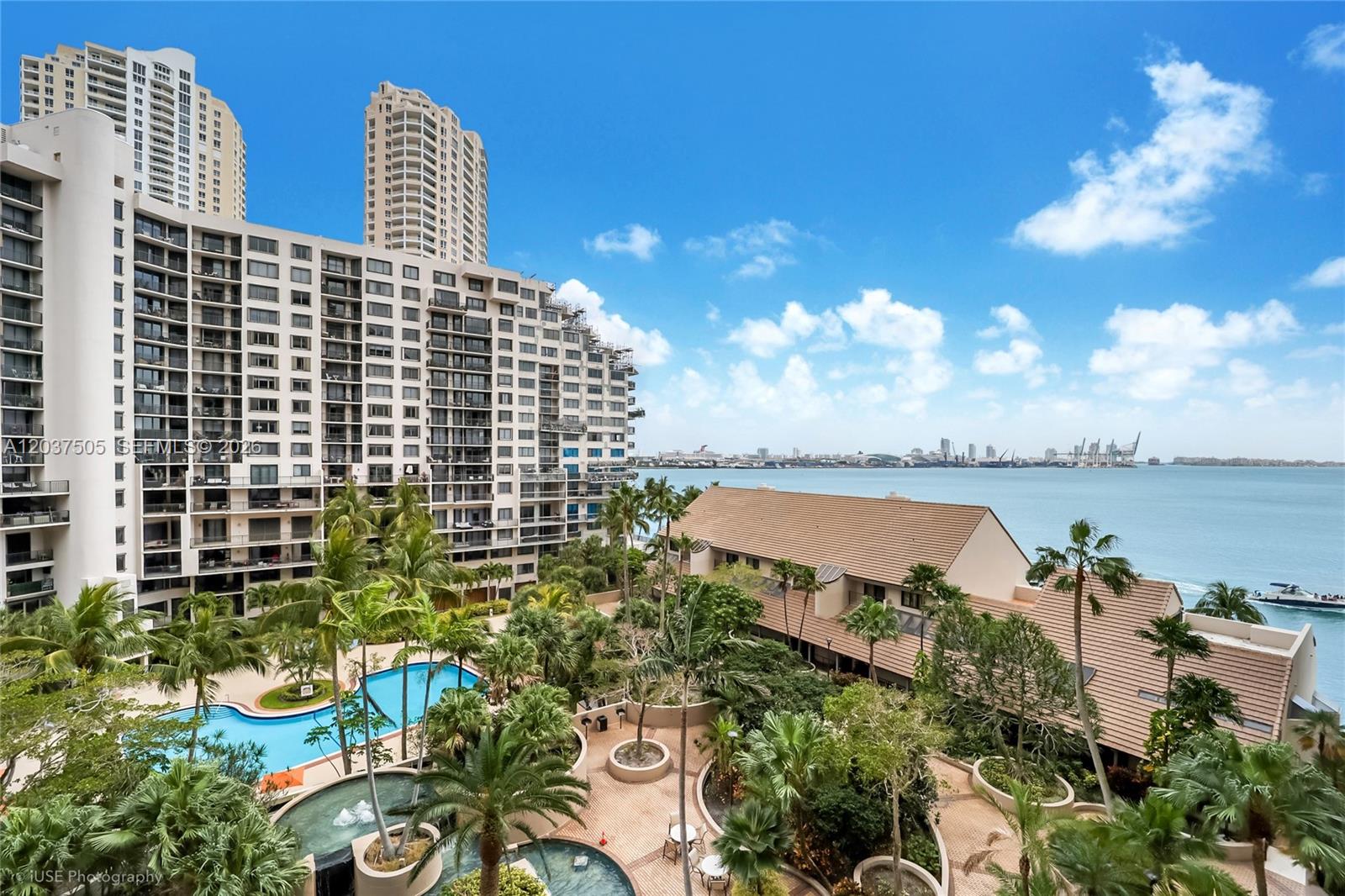 An elevated view shows a swimming pool, lush landscaping, and a large apartment complex overlooking water — 520 Brickell Key Dr # A802, Miami FL 33131, MIAMI, FL