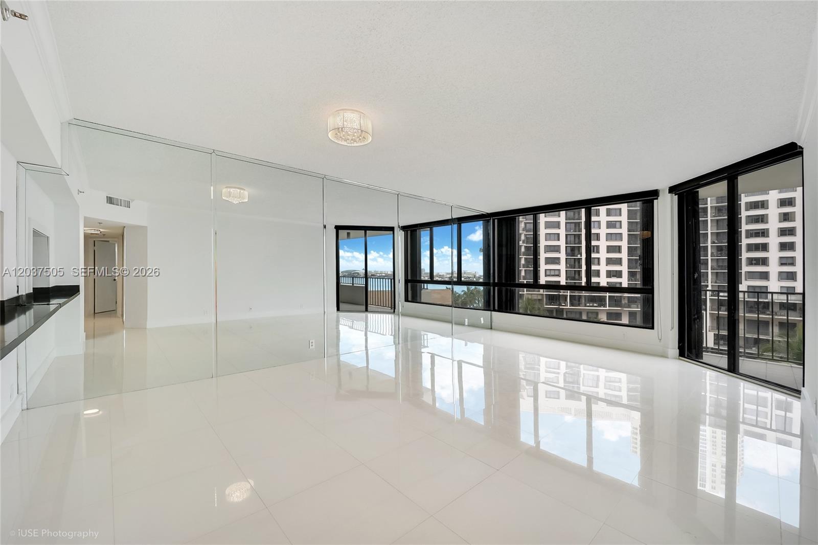 A bright, empty room features white tile floors, a mirrored wall, and floor-to-ceiling windows — 520 Brickell Key Dr # A802, Miami FL 33131, MIAMI, FL