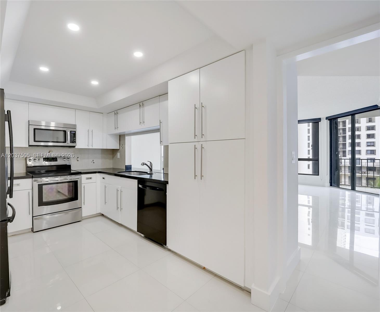 A modern kitchen features white cabinets, stainless steel appliances, and black countertops — 520 Brickell Key Dr # A802, Miami FL 33131, MIAMI, FL