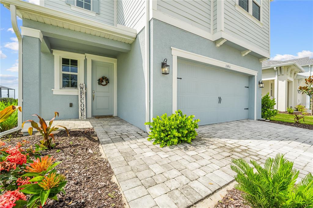 A light blue two-story house features a paved driveway, a front door, and landscaping — 15951 MULRION BOULEVARD, PUNTA GORDA, FL