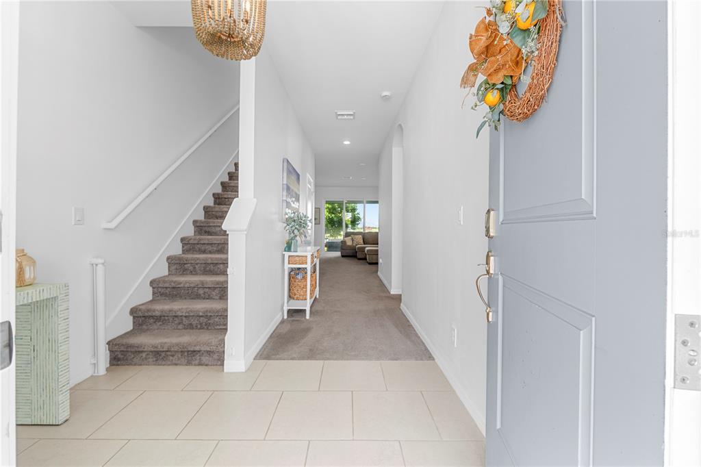 An entryway features tile flooring, a carpeted staircase, and a view into the living area — 15951 MULRION BOULEVARD, PUNTA GORDA, FL