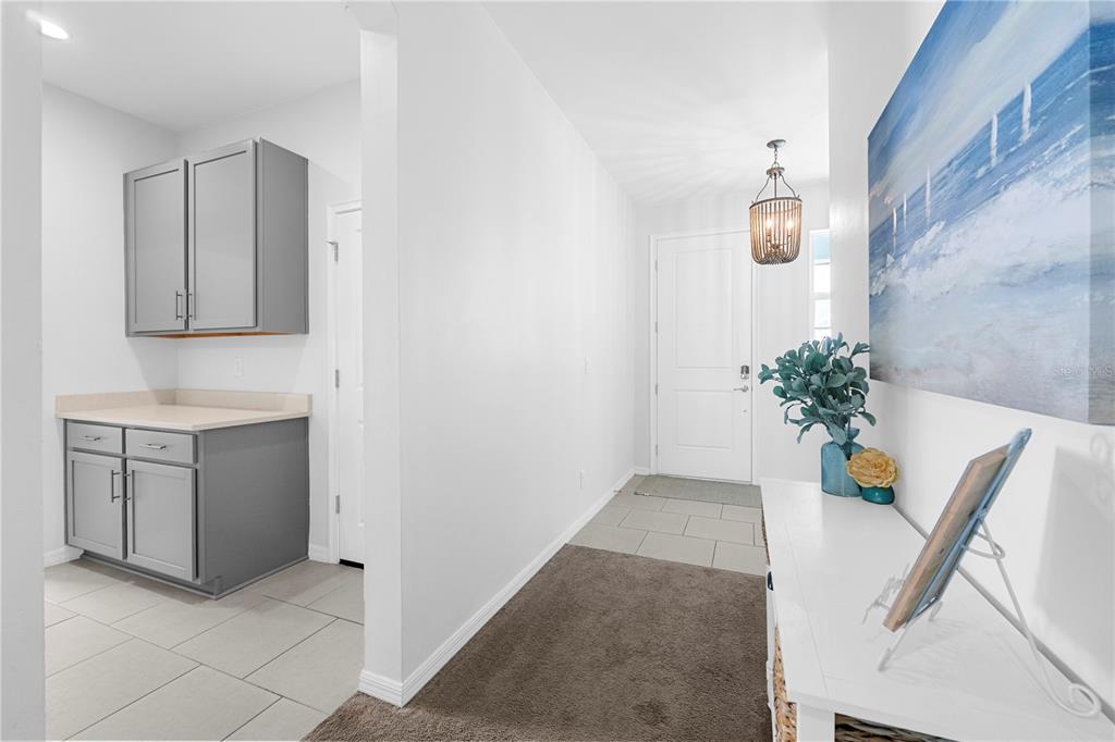 A bright entryway features a white front door, gray cabinetry, and a console table — 15951 MULRION BOULEVARD, PUNTA GORDA, FL