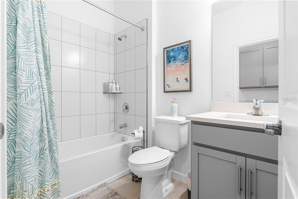 A bathroom features a gray vanity, a white toilet, and a shower-tub combo with white tiles — 15951 MULRION BOULEVARD, PUNTA GORDA, FL