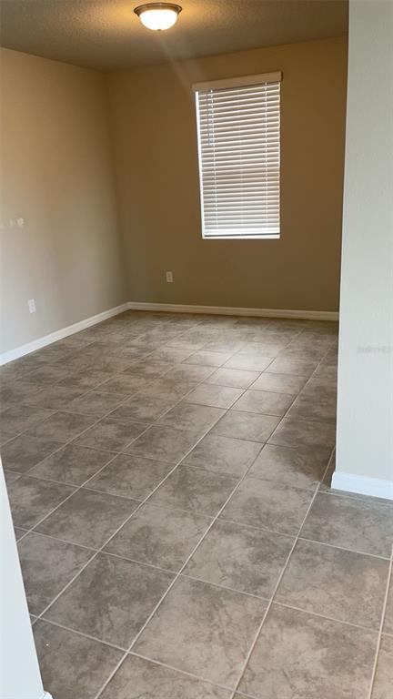 An empty room features light-colored walls, a single window with blinds, and tiled flooring — 10217 DAYBREAK GLEN, PARRISH, FL