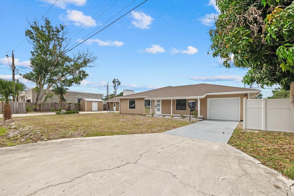 A single-story house with tan siding, a white garage door, and a concrete driveway — 2818 OLYMPIC STREET, SARASOTA, FL