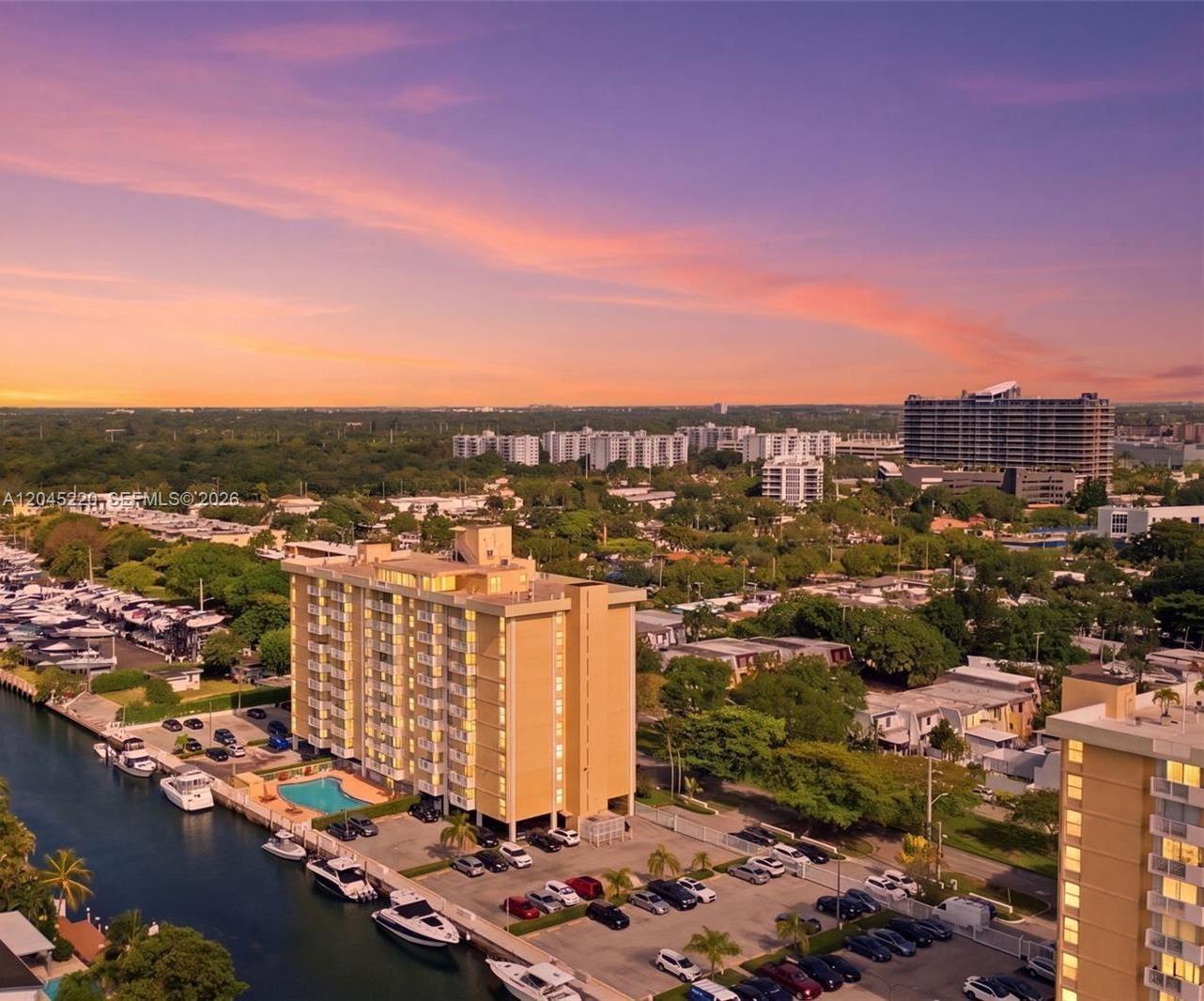 An aerial view shows a tan apartment building with a pool and boat slips — NORTH MIAMI, FL