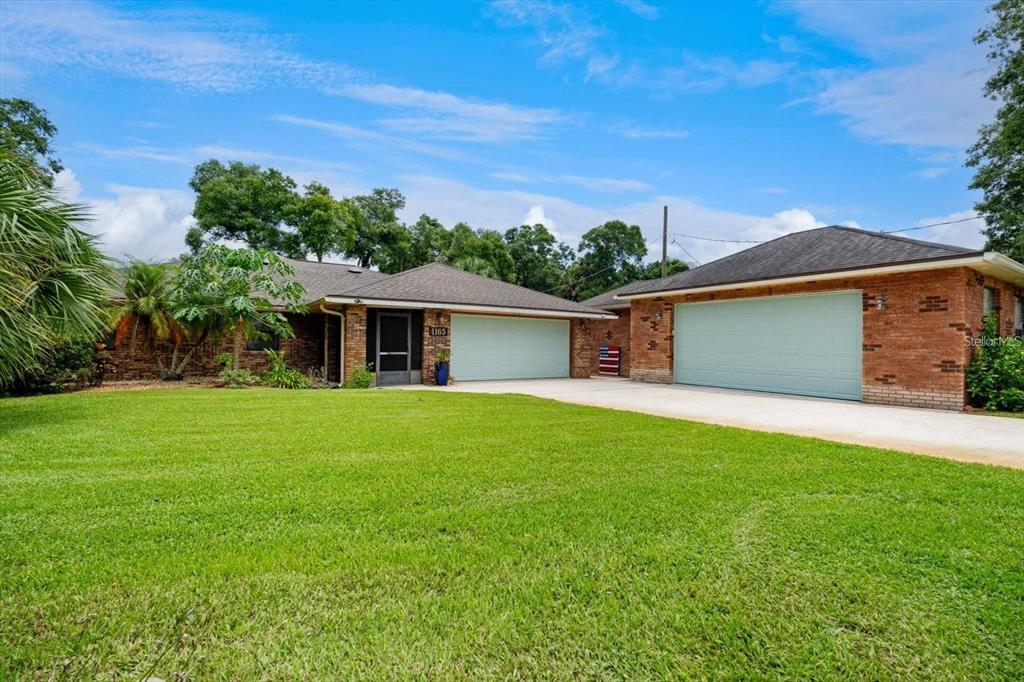 A single-story brick house features two separate garage doors and a large front lawn — 1165 GEORGE ANDERSON STREET, ORMOND BEACH, FL