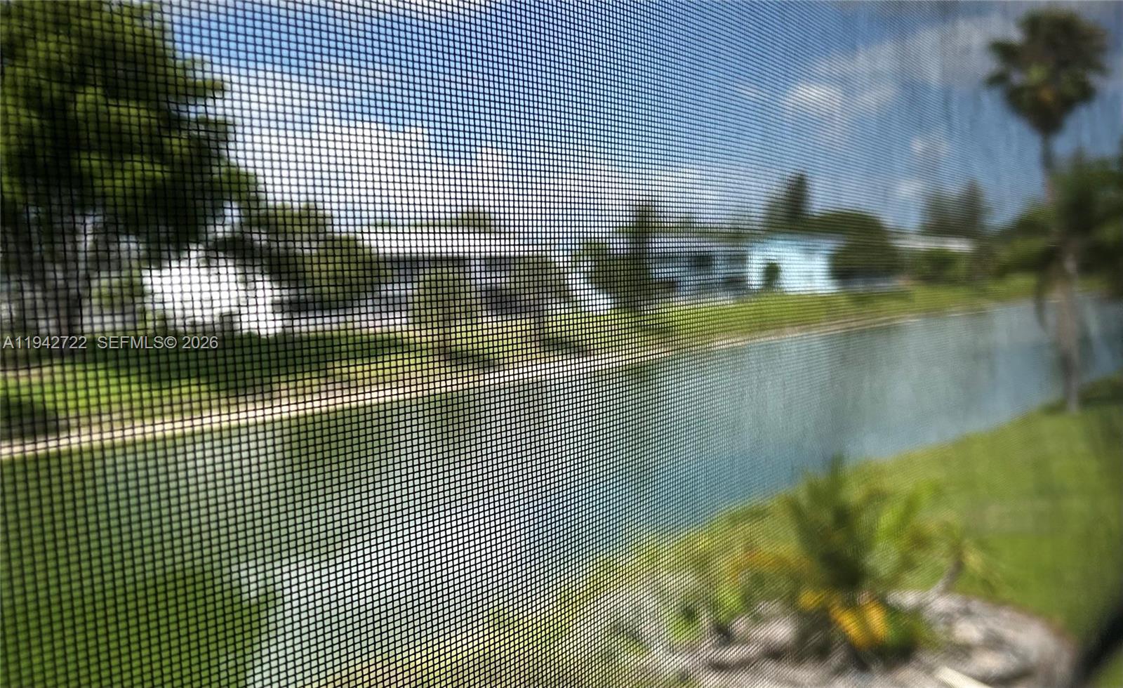 A view of a canal and neighboring buildings seen through a screened-in porch — 38 Northampton B # 38, West Palm Beach FL 33417, WEST PALM BEACH, FL