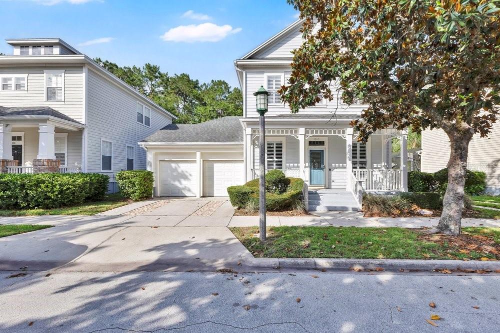 A two-story light gray house with a front porch, two-car garage, and a large tree — 1013 MAIDEN TERRACE, CELEBRATION, FL