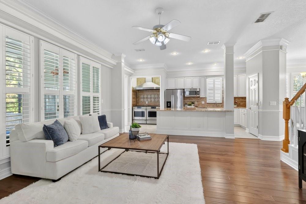 A living room with a white sofa and coffee table opens to a white kitchen — 1013 MAIDEN TERRACE, CELEBRATION, FL