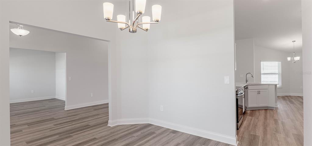 A dining area with a chandelier, light gray walls, and wood-look flooring — 1496 MELROSE STREET, LAKE ALFRED, FL