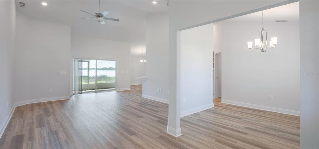 An open-concept living and dining area with light wood-look flooring and a water view — 1496 MELROSE STREET, LAKE ALFRED, FL