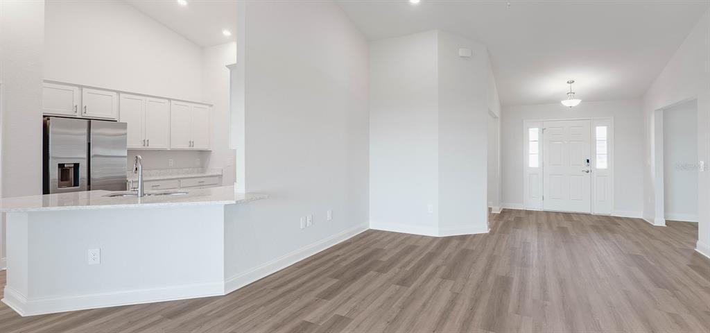 A kitchen with white cabinets and a breakfast bar opens into a light-filled entryway — 1496 MELROSE STREET, LAKE ALFRED, FL