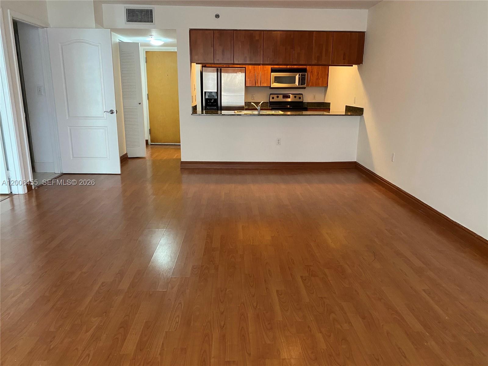An open living area features wood-look flooring and a kitchen with dark wood cabinets — 1200 Brickell Bay Dr # 1914, Miami FL 33131, MIAMI, FL