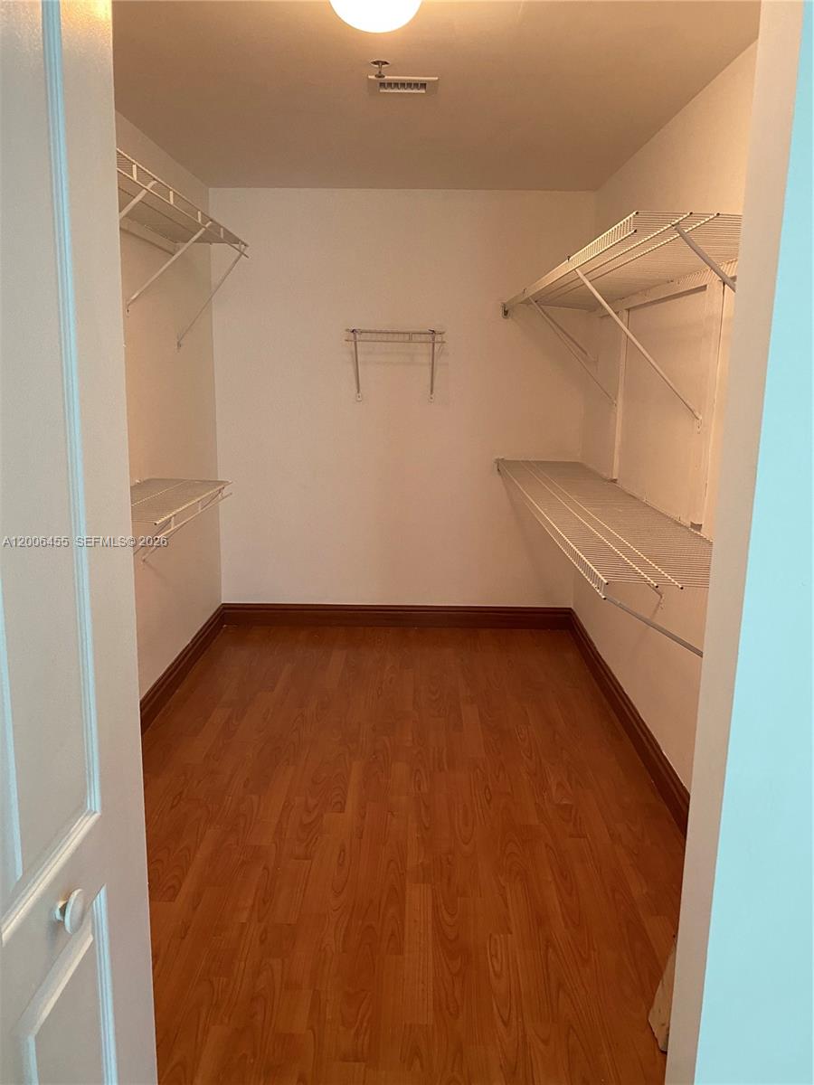 A walk-in closet features white wire shelving, light wood-look flooring, and a ceiling light — 1200 Brickell Bay Dr # 1914, Miami FL 33131, MIAMI, FL