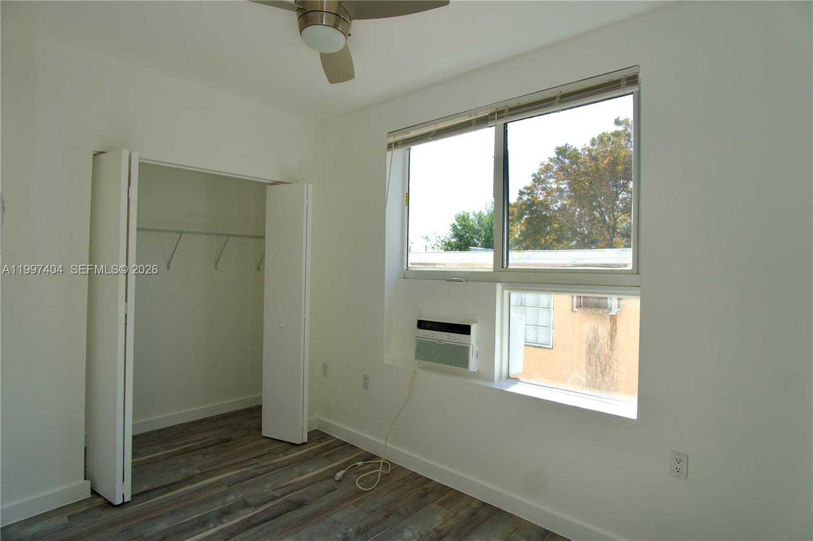 A bedroom features a closet, a ceiling fan, wood-look flooring, and a window air conditioner — 1036 SW 5th St # 12, Miami FL 33130, MIAMI, FL