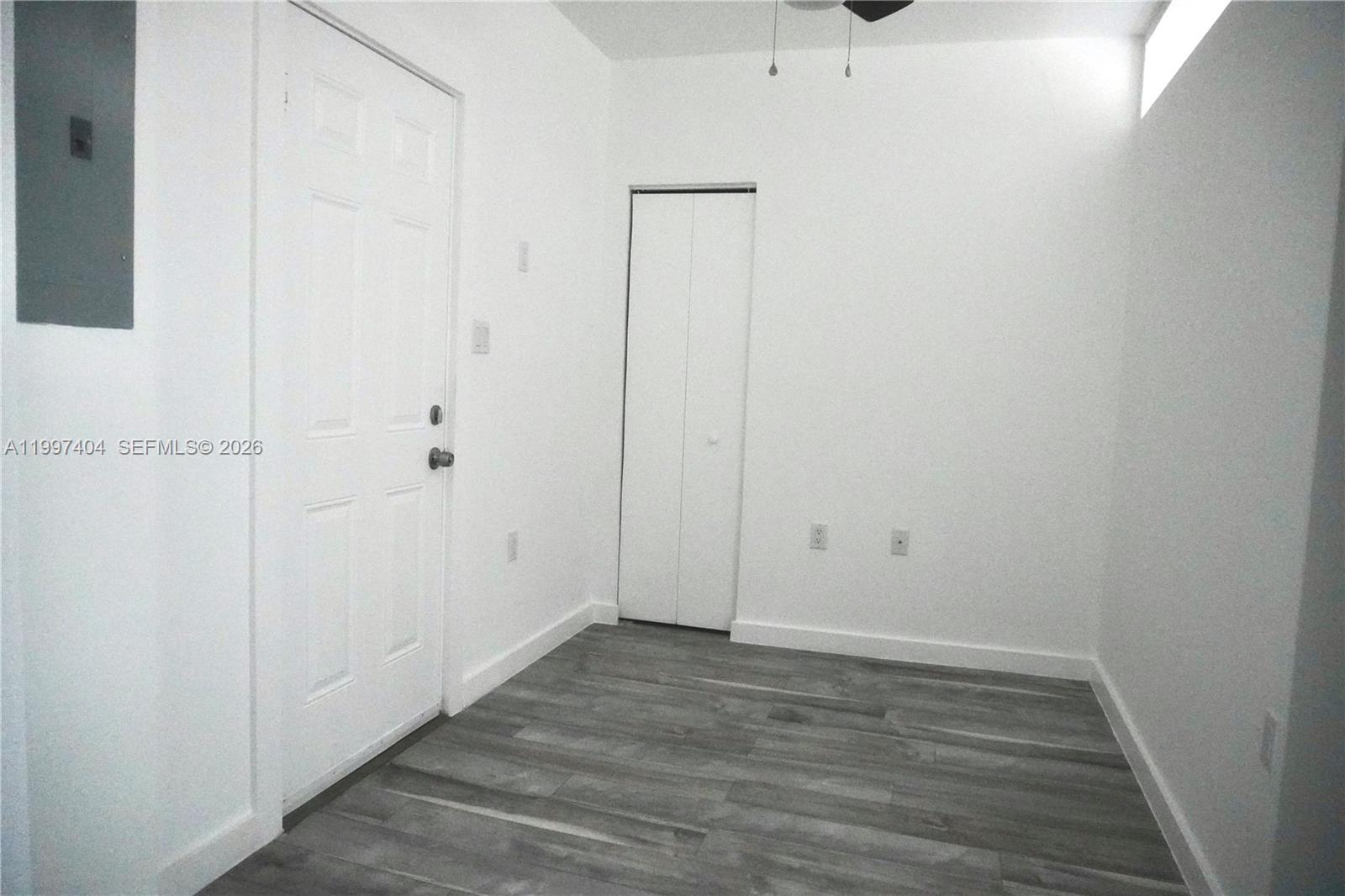 An empty room features white walls, gray wood-look flooring, a white door, and a closet — 1036 SW 5th St # 12, Miami FL 33130, MIAMI, FL