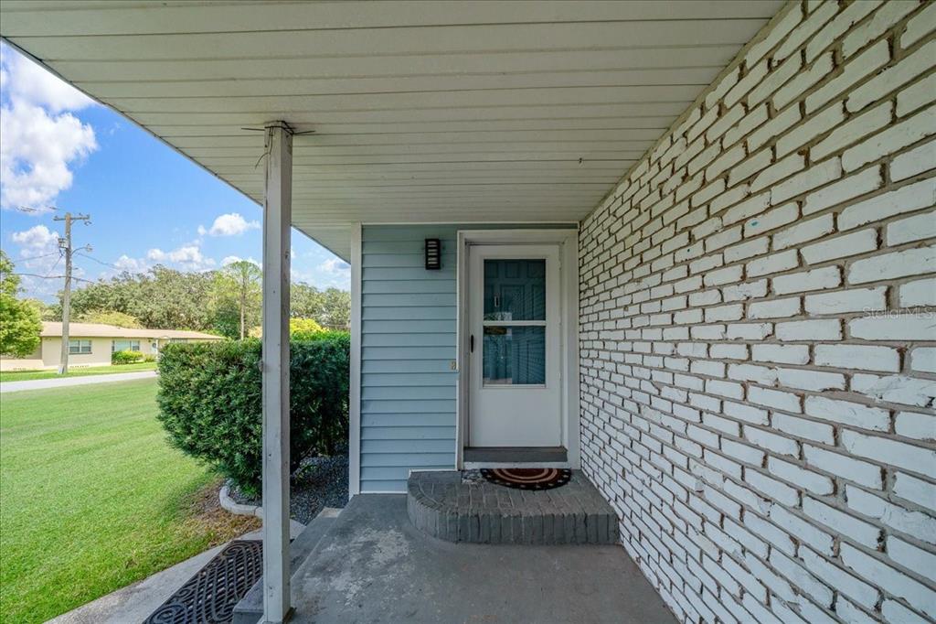 A covered porch features a white brick wall, blue siding, and a single front door — 2830 SE 6TH STREET, OCALA, FL