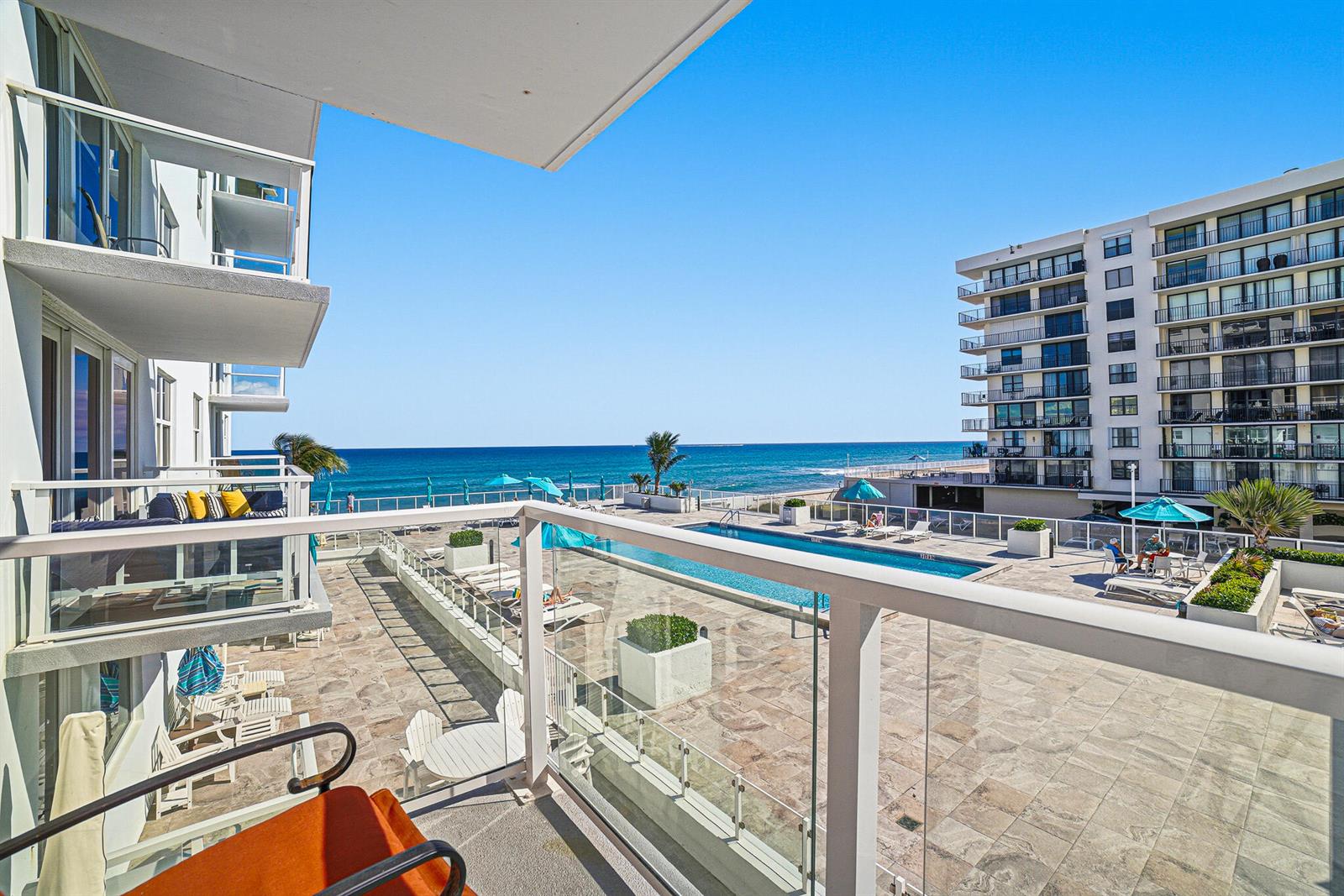 A balcony view overlooking a swimming pool, a stone patio, and the ocean — 3450 S Ocean Boulevard # 211, Palm Beach FL 33480, PALM BEACH, FL