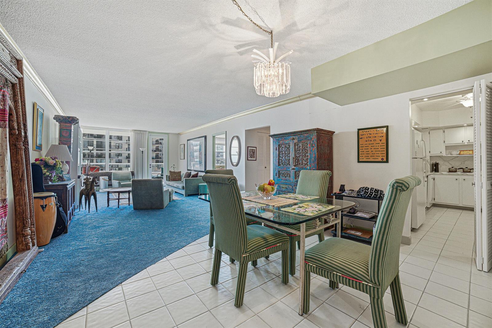 A dining area with striped chairs and a glass table sits beside a blue-carpeted living room — 3450 S Ocean Boulevard # 211, Palm Beach FL 33480, PALM BEACH, FL
