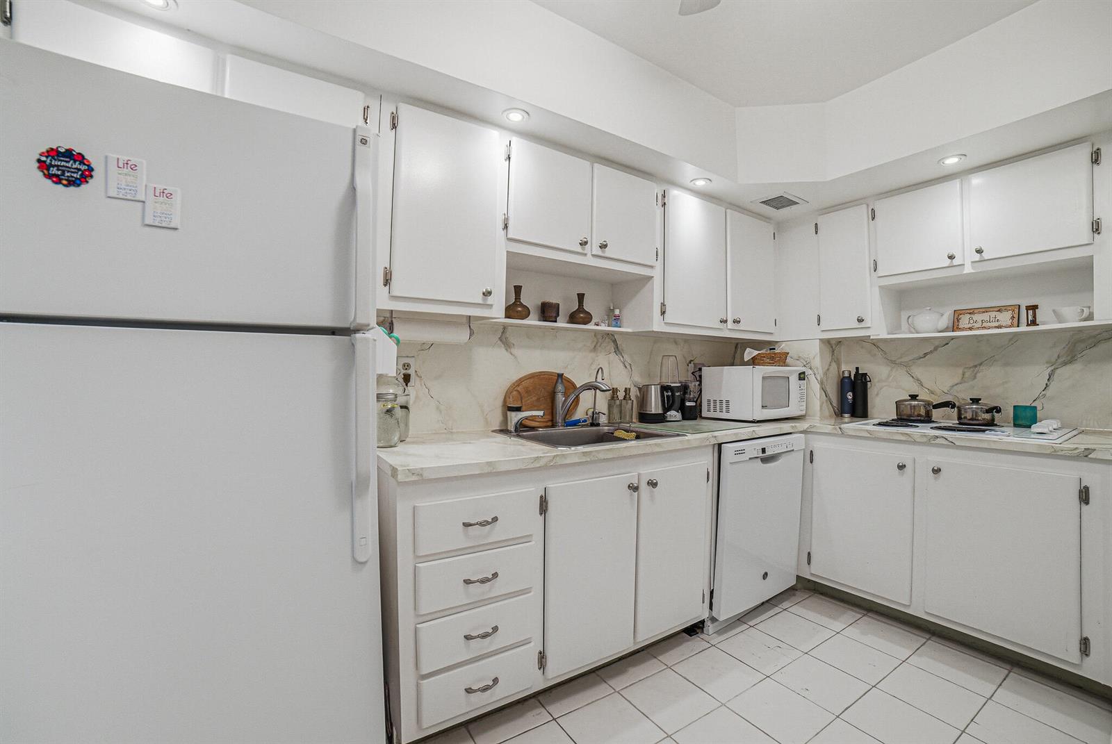 A white kitchen features white cabinets, a laminate countertop, and a tiled floor — 3450 S Ocean Boulevard # 211, Palm Beach FL 33480, PALM BEACH, FL