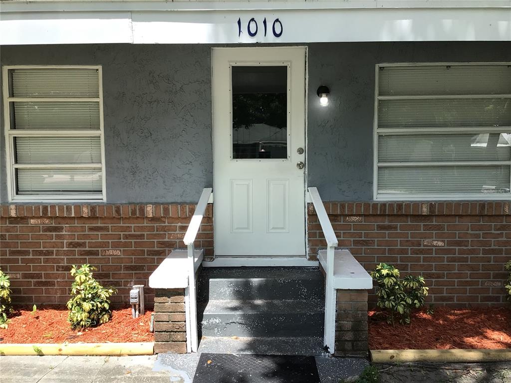 A front exterior view of a house with a white door, brick base, and windows — 1010 DAKOTA AVENUE, ST CLOUD, FL