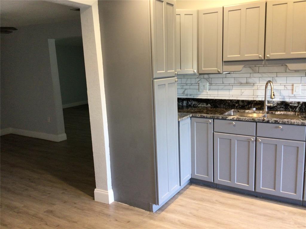 A kitchen features gray cabinets, granite countertops, and white subway tile backsplashes — 1010 DAKOTA AVENUE, ST CLOUD, FL