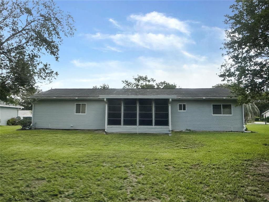 The rear exterior of a single-story house features gray vinyl siding and a screened porch — 11248 SW 76TH TERRACE, OCALA, FL