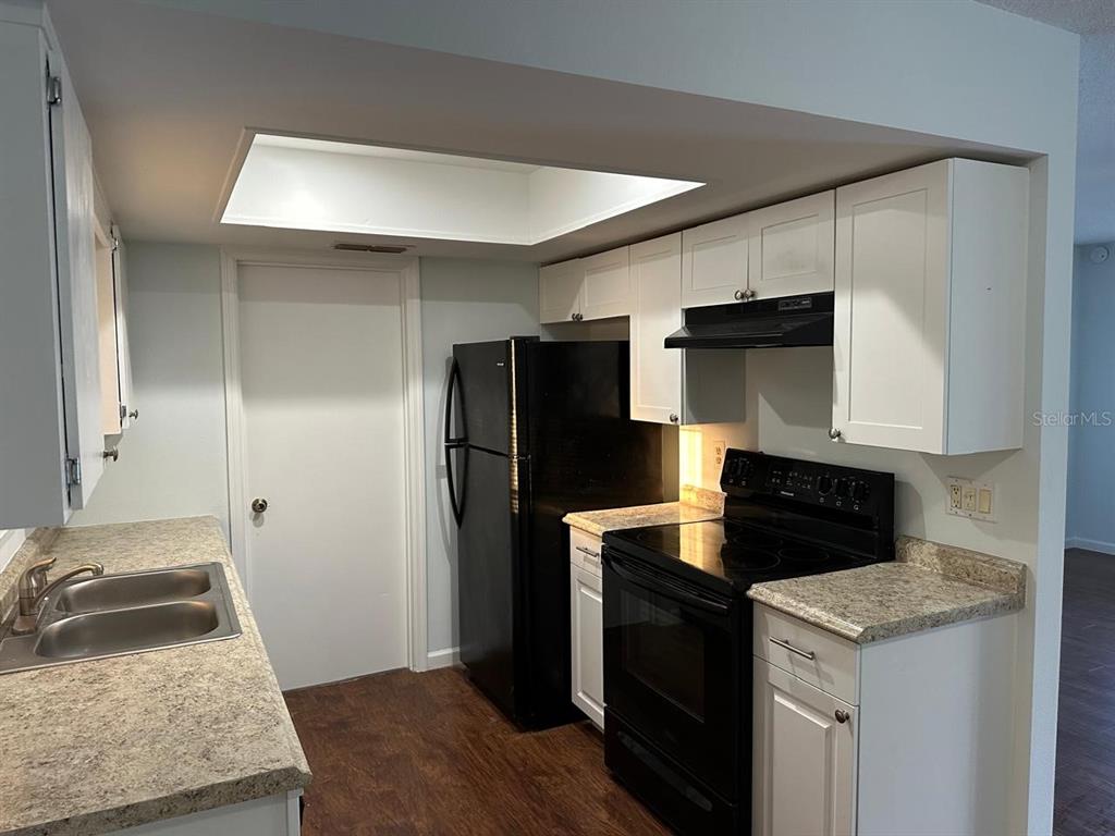 A kitchen features white cabinets, black appliances, and speckled laminate countertops — 11248 SW 76TH TERRACE, OCALA, FL