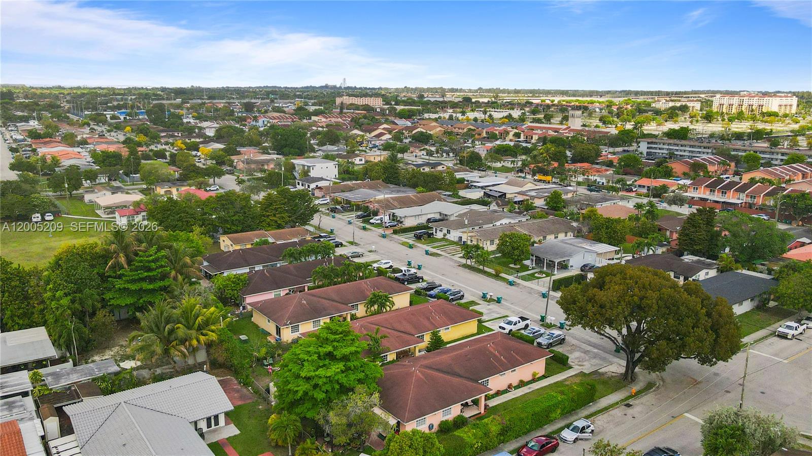An aerial view shows a suburban neighborhood with single-story houses, tree-lined streets, and parked cars — 11002 SW 3rd St, Sweetwater FL 33174, SWEETWATER, FL