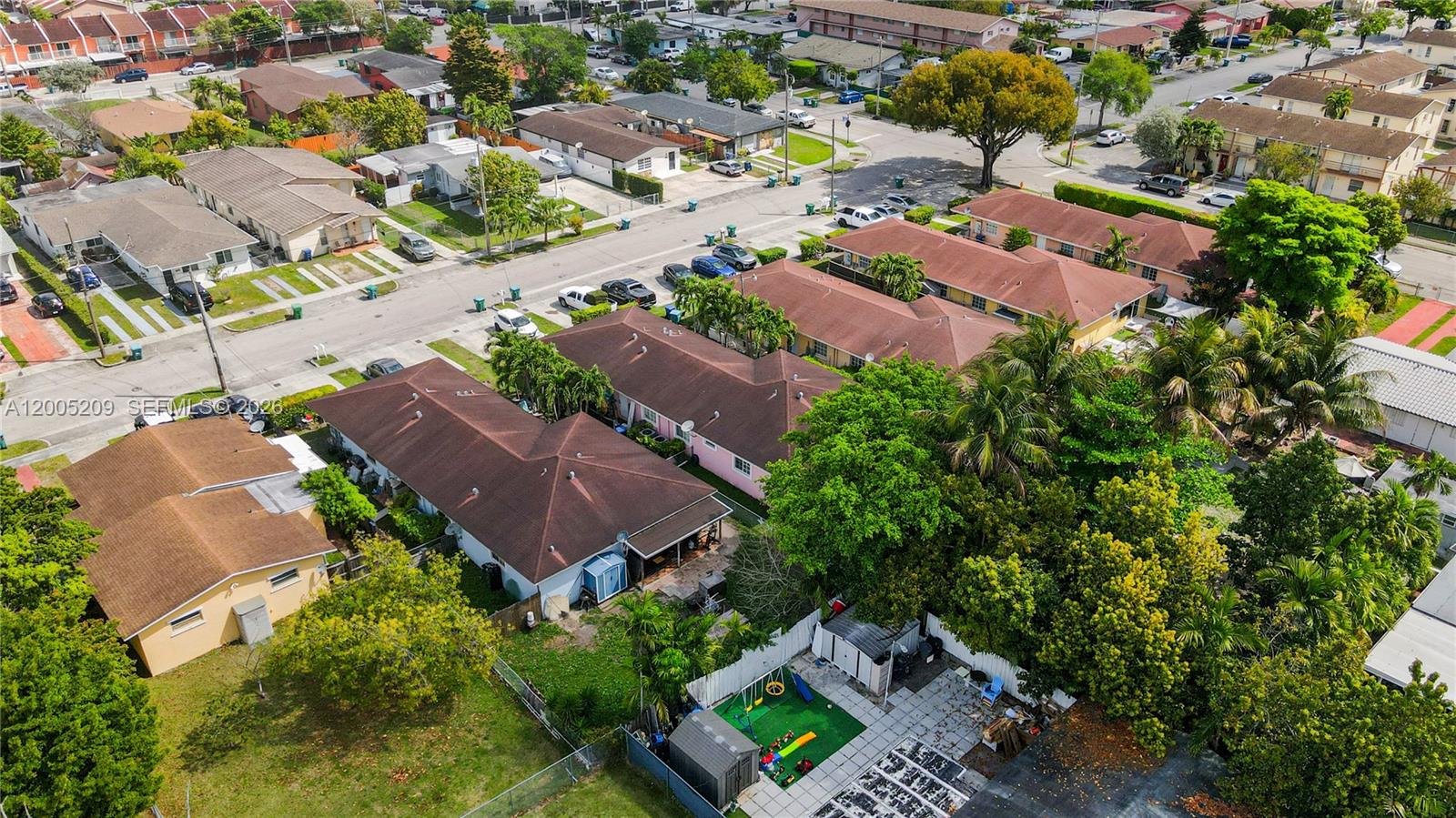 An aerial view shows a residential neighborhood with single-story homes, paved streets, and lush trees — 11002 SW 3rd St, Sweetwater FL 33174, SWEETWATER, FL