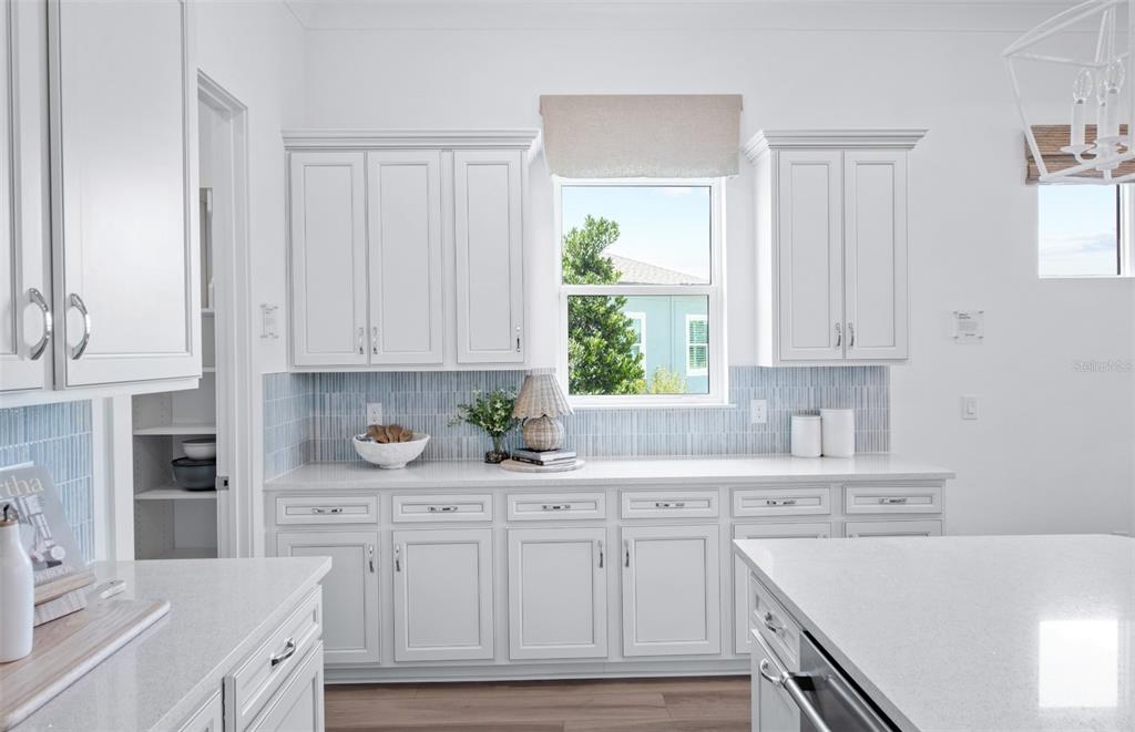 A bright kitchen features white cabinetry, a light blue tiled backsplash, and a central island — 6248 SW 82ND TERRACE ROAD, OCALA, FL