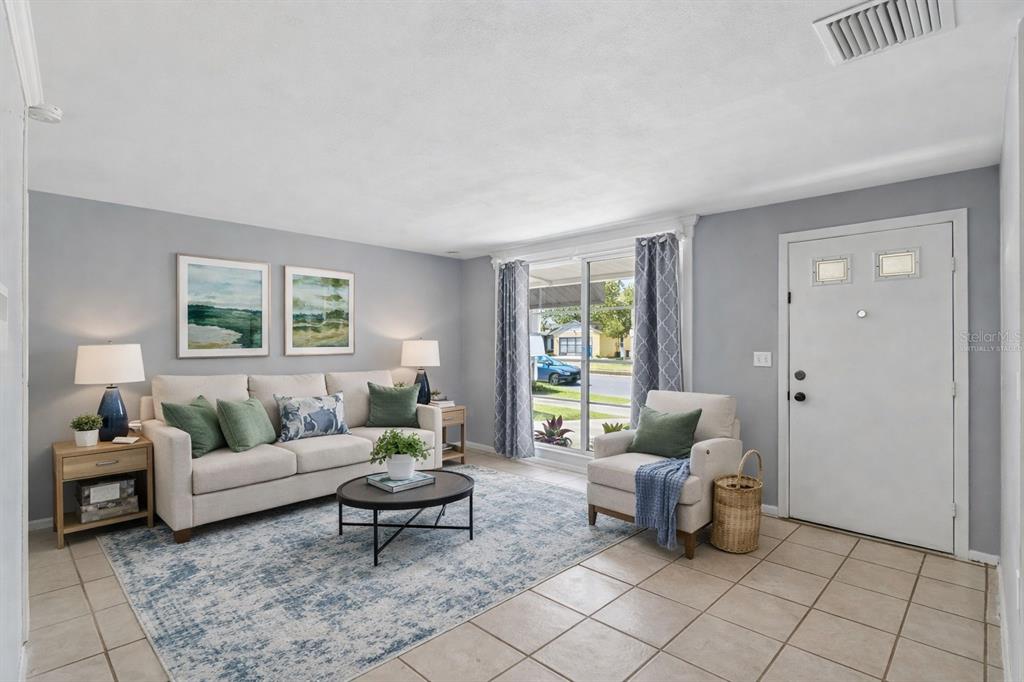 A living room features a beige sofa, an armchair, a coffee table, and tiled flooring — 3640 MURROW STREET, NEW PORT RICHEY, FL