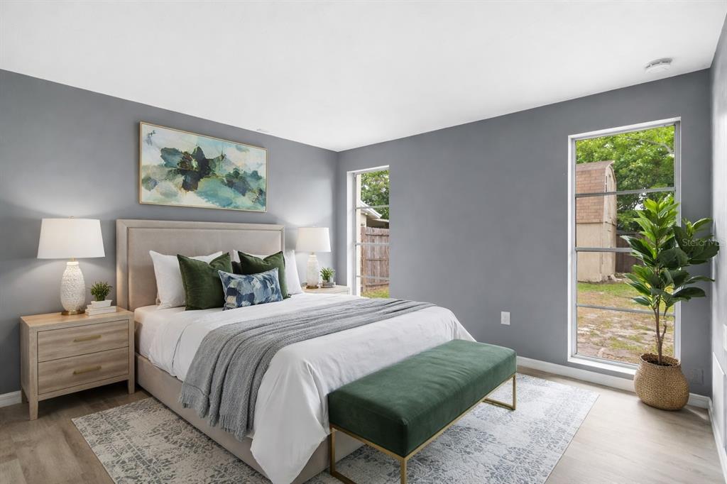 A bedroom with gray walls, a queen bed, a green bench, and two large windows — 3640 MURROW STREET, NEW PORT RICHEY, FL