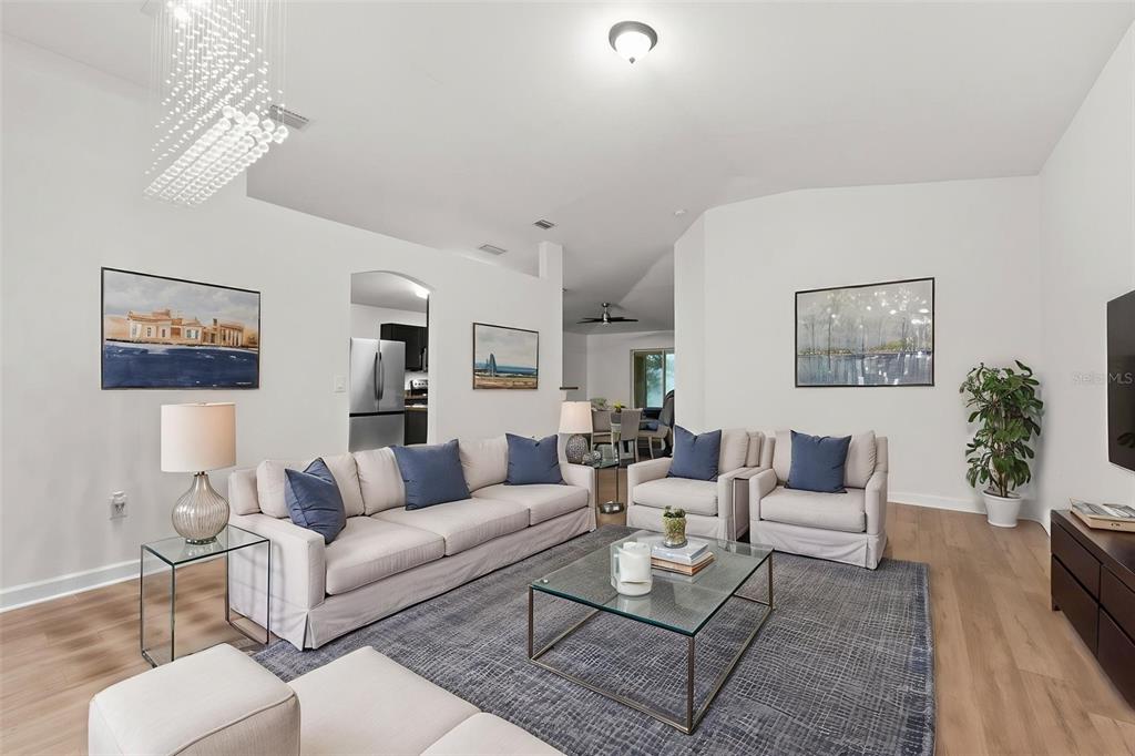 A bright living room features a sofa, two armchairs, a glass coffee table, and artwork — 1319 TARTON WAY, COCOA, FL