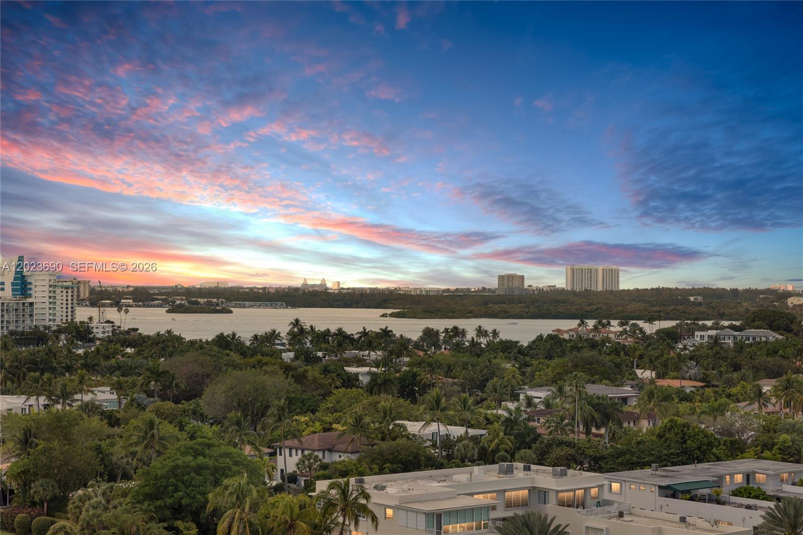 An elevated view shows a sunset over a bay, lush trees, and residential buildings — 9801 Collins Ave # 11M, Bal Harbour FL 33154, BAL HARBOUR, FL