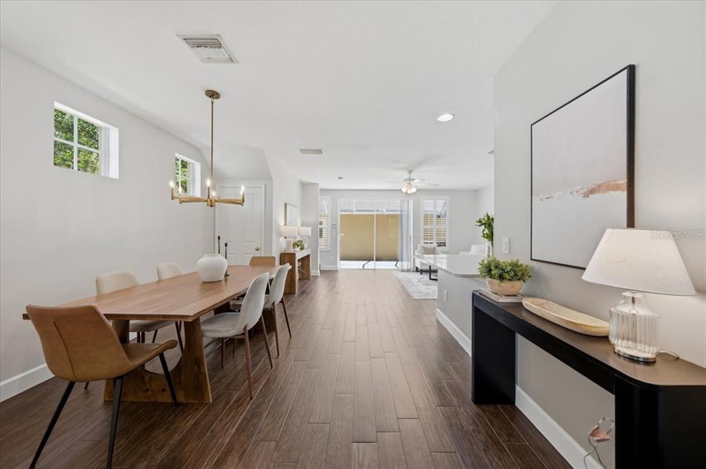 A dining area with a wooden table and chairs leads to a living room with sliding doors — 9530 W PARK VILLAGE DRIVE, TAMPA, FL