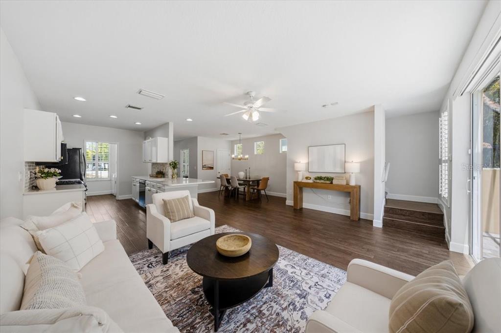 An open-concept living and dining area features white cabinetry, dark wood floors, and neutral furniture — 9530 W PARK VILLAGE DRIVE, TAMPA, FL