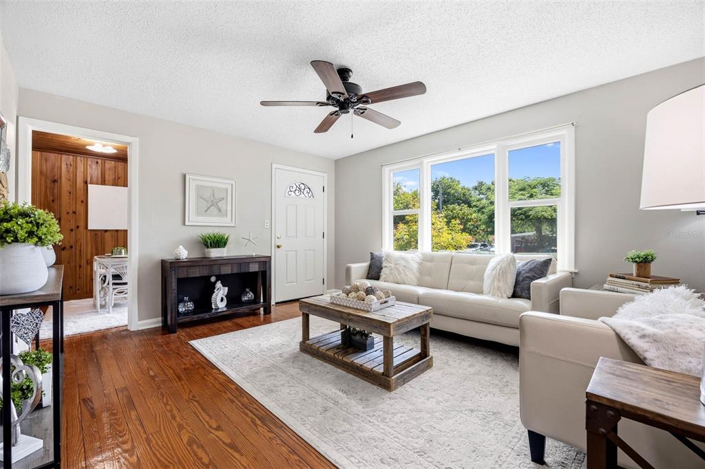 A living room features a white sofa, a wooden coffee table, and a ceiling fan — 1024 MICHIGAN DR E, DUNEDIN, FL